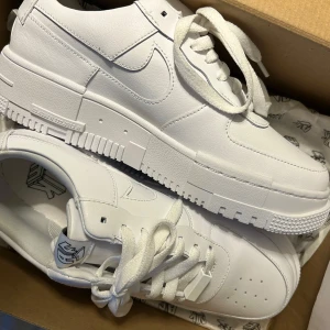 Nike Air Force 1 Pixel AF1 - Fick dom som present aldrig använda nypris 1300-1700 kr Nike Air Force 1 Pixel i helvitt skinn med chunky platt sula och klassisk snörning. Snygg minimalistisk design med diskreta detaljer och rund tå. Perfekta för dig som vill ha en clean och modern sneaker-look.