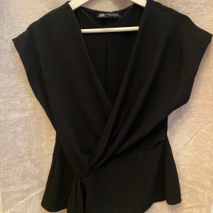 Svart omlottopp från Zara - Skit snygg, populär och slutsåld svart topp. Säljs för att jag har två. Den har några trådar utdragna men inget man tänker på.