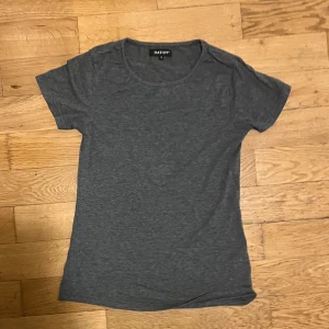 Grå t-shirt från Take Off - Säljer en enkel och stilren grå t-shirt från Take Off. Den har en rund halsringning och korta ärmar, perfekt för en avslappnad look. Passar bra till jeans eller shorts.