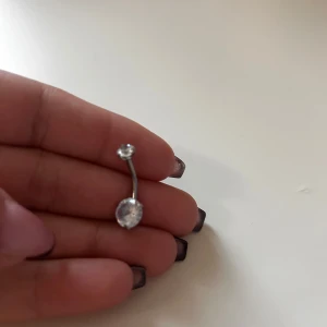 Silver navelpiercing med stenar - Snygg navelpiercing i silver med två glittrande stenar. Perfekt för att ge lite extra bling till din stil. Passar bra till både vardag och festliga tillfällen. Aldrig använd fick två stycken 