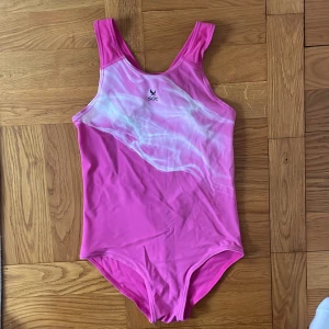 Rosa baddräkt från SOC - Snygg rosa baddräkt från SOC med ett vitt mönster framtill. Perfekt för simträning eller en dag på stranden. Den har en klassisk skärning och är tillverkad i ett bekvämt material.