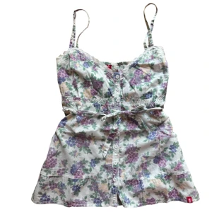 Blommig linnetopp från edc - Söt blommig linnetopp från edc med knappar framtill och ett knytband i midjan. Strl M men passar mindre oxå pga knytband i midjan och justerbara axelband. 