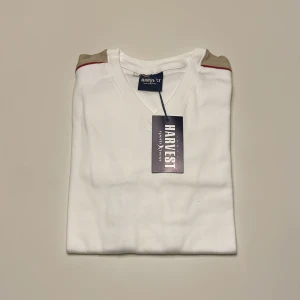 Vit långärmad tröja från Harvest - Helt ny och snygg vit långärmad tröja från Harvest med beige och röda detaljer längs axlarna och ärmarna. Perfekt för en stilren look. Tröjan har en v-ringad hals och är tillverkad i ett mjukt material. Nypris runt 800-1000kr om jag har kollat rätt men är inte helt 100! Jag går efter det jag hittade och säljer den för endast 399! 