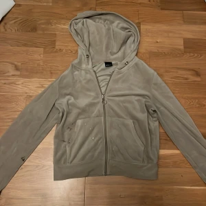 Beige hoodie från Gina Tricot - Säljer en beige hoodie från Gina Tricot med dragkedja och huva. Den har långa ärmar och två fickor framtill. Den har några märken, vet ej om det går bort i tvätten.