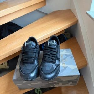 Svarta sneakers från Valentino - Snygga svarta sneakers från Valentino med klassisk design och bekväm passform. Skorna har en stilren look med svarta snören och en diskret logga på plösen. Perfekta för en trendig vardagsstil.