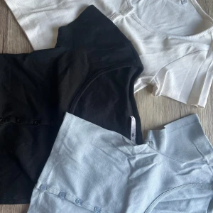 Tre ribbade kortärmade toppar - Säljer tre ribbade toppar i svart, vit och ljusblå. Alla har korta ärmar och knappar framtill.  Den svarta toppen har jag använt enstaka gånger, De andra 2 är helt oanvända:-) 