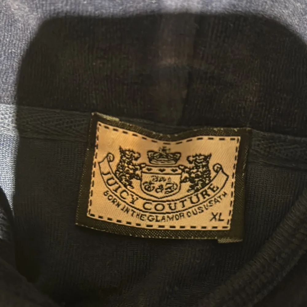 Säljer en snygg mörkblå velourjacka från Juicy Couture med dragkedja och huva. Jackan har ett stort, detaljerat broderi på ryggen med guld- och rosa detaljer samt ett mindre broderi framtill. Perfekt för en glamorös look!. Takit.