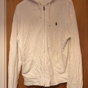 Vit hoodie från Ralph Lauren - Säljer en klassisk vit hoodie från Ralph Lauren välgigt  bekväm, perfekt för en avslappnad stil. Tröjan har används 3 till 4 gånger väldigt bra skick som ny. Storlek M man passar L, hör gärna av er vid frågor. Pris kan diskuteras😁