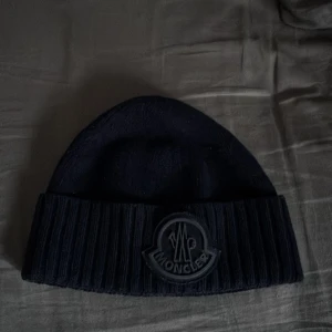 Mörkblå mössa från Moncler - Snygg svart mössa från Moncler med ribbad kant och ett broderat Moncler-märke.