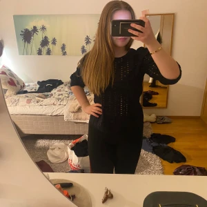Svart blus från KappAhl - Säljer en elegant svart blus från KappAhl med ett unikt hålmönster. Blusen har långa ärmar och en rund halsringning, perfekt för att ge en stilren look. Passar bra till både jeans och kjol. Perfekt för dig som vill ha något speciellt i garderoben!