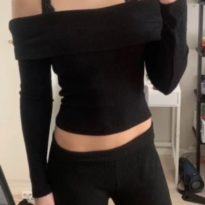 Svart ribbad offshoulder topp - Snygg svart ribbad offshoulder topp med långa ärmar. Perfekt för en stilren look. Toppen är croppad och har en elegant design som passar till många tillfällen. (Inte min bild på första bilden)
