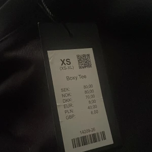 Svart Boxy Tee från 157 - Säljer en stilren svart Boxy Tee från 157. T-shirten har en boxig passform och är perfekt för en avslappnad look. Den är tillverkad i ett mjukt material som känns skönt mot huden.