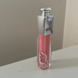 Rosa läppglans från Dior - Elegant rosa läppglans från Dior med en skimrande finish. Förpackningen är stilren med en silverfärgad kork och den ikoniska Dior-loggan. Perfekt för att ge läpparna en glansig och lyxig look.,har inte kommit till användning så jag säljer den ,blir inte så rosa på läpparna (köptes ifrån kicks)