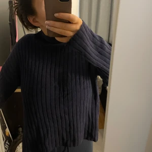 Mörkblå ribbad tröja - Säljer en snygg mörkblå ribbad tröja med långa ärmar och halvpolokrage. Tröjan har en bekväm passform och slits längst ner på sidorna 