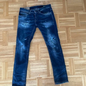 Dondup George skinny 31 - Snygga blå jeans med coola slitningar och en klassisk femficksdesign. De har en dragkedja och knapp framtill. Perfekta för en avslappnad stil med en touch av edge.