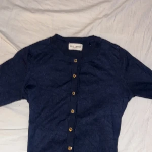 mörkblå kofta från Holly & White - säljer en stilren mörkblå kofta från Holly & White med knappar i guld. koftan är nästan aldrig använd, den är i jättefint skick och det finns inga skador på koftan. kom privat vid frågor eller fler bilder! pris kan diskuteras