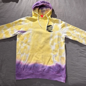 Gul och lila hoodie från Santa Cruz - Säljer en cool tie-dye hoodie från Santa Cruz i gult och lila storlek S. Försiktigt använd ett fåtal gånger. Den har en stor logga på ryggen och en mindre på bröstet. Tillverkad i 100% ekologisk bomull, perfekt för en avslappnad stil. Hör av dig vid intresse! Nypris: Ca 800-900kr