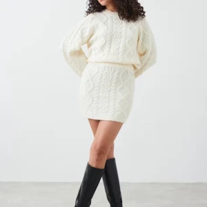 Offwhite stickad kjol från Gina Tricot - Naturvit kabelstickad kjol. Köpt på Gina Tricot, i storlek S. Resår i midjan. Säljes i nyskick! Kjolen är oanvänd. 🧶✨Mått: längd 45 cm, midjevidd: 70-100 cm. 5% ull.