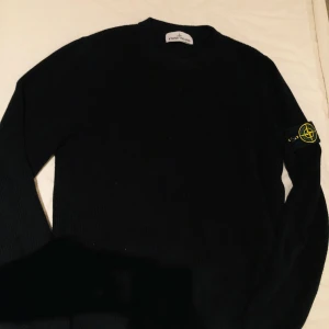 Svart tröja från Stone Island - Säljer en stilren svart tröja från Stone Island med deras ikoniska märke på ärmen. Tröjan har en ribbad struktur och långa ärmar, perfekt för en avslappnad men snygg look.är s men sitter som m
