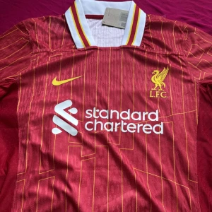 LIVERPOOL HEMMATRÖJA 24/25 - Säljer denna snygga liverpool hemma tröjan i storlek M för 24/25 säsongen med ALEXANDER  TRENT ARNOLD på ryggen. tröjan är helt ny och oanvänd med tagg. Pris kan diskuteras skriv gärna vid funderingar eller för mer bilder. Postar samma dag vid köp