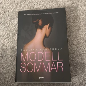 Modellsommar - Säljer boken 'Modellsommar' av Paulina Porizkova. En roman om livet bakom modevärldens kulisser, med svart omslag och rosa text. Perfekt för dig som gillar berättelser om mode, glamour och personliga resor.
