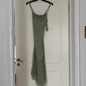 Ljusgrön långklänning med smala axelband - Säljer en ljusgrön långklänning med smala, justerbara axelband och asymmetrisk nederkant. Klänningen har en elegant och enkel design, perfekt för sommarens tillfällen. Materialet känns lätt och följsamt.