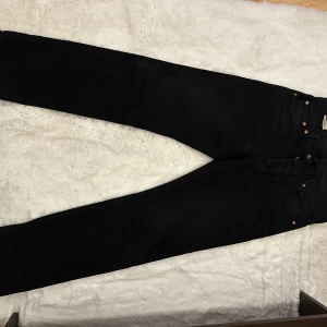 Svarta Levi's 501 jeans W30 L30 - Säljer ett par klassiska svarta Levi's 501 jeans i modellen straight. Jeansen har knappar i gylfen och är tillverkade i ett robust denimtyg. Passar perfekt för dig som gillar tidlös stil och vill ha ett par jeans som funkar till allt.