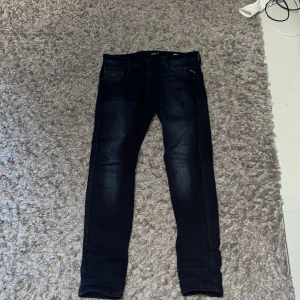 Mörkblå Replay Anbass jeans slim fit - Säljer ett par mörkblå Replay Anbass jeans slim fit. Replay-läderpatch bak. Storleken är 29/30. Snygga utan några defekter. 