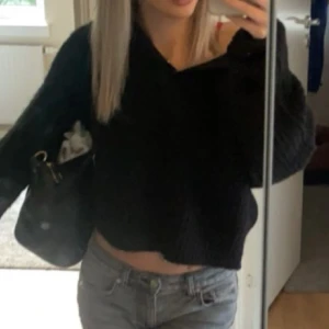 Svart stickad tröja från Gina Tricot - Säljer en svart stickad tröja från Gina Tricot. Tröjan har en v-ringad design och är perfekt för kyligare dagar. Den är mjuk och bekväm med en stilren look. Passar bra till både jeans och kjol.