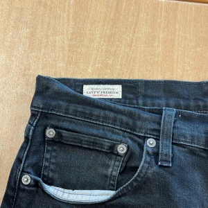 Svarta Levi's 502 jeans - Säljer ett par svarta Levi's 502 jeans med klassisk femficksdesign och raka ben. Jeansen har en svart läderpatch bak i midjan och Levi's röda logga på bakfickan. Perfekta för en stilren och avslappnad look. W:31 L:32