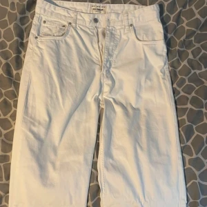 Vita jeansbyxor från Pull&Bear - Säljer ett par vita jeansbyxor från Pull&Bear med klassisk femficksdesign och dragkedja. Byxorna har raka ben och normal passform, perfekta för en clean och stilren look.