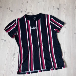 T-shirt - Randig T-shirt från hollister! Tröjan är inköpt i USA för några år sedan. Svart vit röd randig med ett snyggt broderat hollister märke på bröstet. Hör av dig vid minsta fundering!🤙🔥