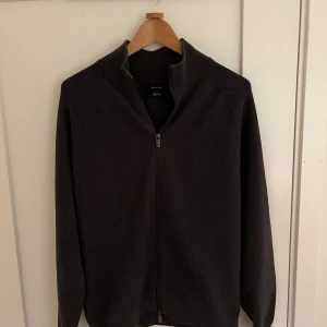 Mörkgrå stickad tröja från Massimo Dutti - Säljer en mörkgrå stickad tröja från Massimo Dutti med dragkedja framtill och hög krage. Tröjan är i väldigt fint skick. Vid frågor eller funderingar hör gärna av dig! 