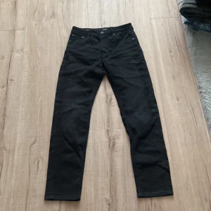 Svarta jeans från Jack & Jones - Säljer ett par svarta jeans från Jack & Jones med klassisk femficksdesign och raka ben. Byxorna har normal passform och är tillverkade i ett slitstarkt jeanstyg. Perfekta för dig som gillar en enkel och stilren look.