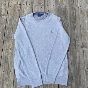 Ljusgrå stickad tröja från Polo Ralph Lauren - Grå tröja från Ralph Lauren i storlek M, skulle säga att den passar 175-180cm.                                                          Tröjan är i bra skick förutom en lagning på ungefär 0,7, 0,5 cm på framsidan.Det är ingenting som syns när man har den på men kolla ändå bild 4 för att avgöra hur stor den är. Hör av er om frågor!