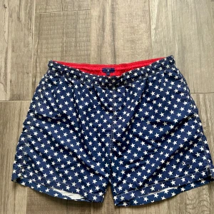 Blå badshorts med stjärnmönster från Gant - Snygga blå badshorts från Gant med vitt stjärnmönster.. Shortsen har snörning i midjan och meshfoder för extra komfort. Perfekta för stranden eller poolen!