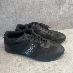 Svarta sneakers från BOSS - BOSS Skor som är väldigt bekväma och sköna att gå i. Dem är ganska välanvända och har slitits på framsidan som man kan se på bilden.