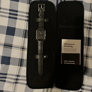 Carl edmond Granit black klocka  - Oanvänd klocka funkar som ny, en helt ny kostar 2800kr. Säljer den för att jag vill inte ha svart. Det ända som behövs göras är byta batteri eftersom har inte använt den. Stilren klocka med svart läderarmband och fyrkantigt silverfärgat boett. Urtavlan är svart med minimalistiska vita markeringar och visare. Kommer i originalfodral med manual.