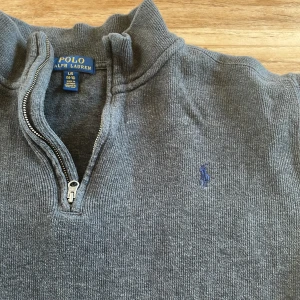 Grå Ralph lauren tröja  - Säljer en grå stickad tröja från Polo Ralph Lauren med dragkedja.                                                Färg: grå, Mycket bra skick som NY, pris kan diskuteras, Storlek: L i barnstorlek motsvarar Xs