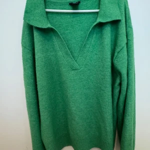 Grön stickad polotröja - Snygg grön stickad tröja med v-ringning och krage. Perfekt för dig som vill ha en enkel men stilren look. Långa ärmar och ribbade muddar ger extra komfort.