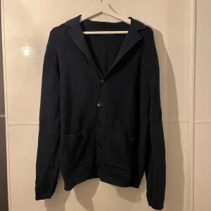 Mörkblå stickad cardigan - Snygg mörkblå stickad cardigan som går perfekt ihop med tex en skjorta under eller bara en basic t-shirt. Inga defekter och helt nytt skick! Hör av er vid funderingar🙌