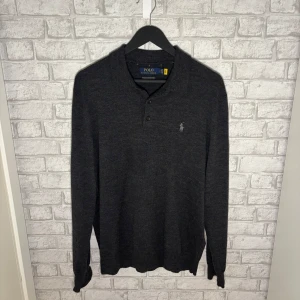 Ralph Lauren merinotröja - Mörkgrå tröja i merinoull från Ralph Lauren, storlek L. Stilren modell med knappar och vit logga på bröstet. Inköpt 2024 och i mycket fint skick, endast använd några enstaka gånger – känns som ny. Hör av dig vid intresse 🙌