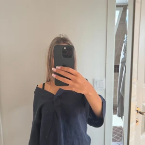 Mörkblå linneskjorta från Morris - Snygg mörkblå skjorta från Morris i luftigt linne. Skjortan har v-ringning, trekvartsärm och en avslappnad passform. Perfekt för varmare dagar när du vill ha en stilren men chill look.