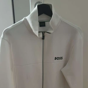 Vit hoodie från hugoboss  - Snygg vit tröja från Hugoboss med stilren design och svart logga på bröstet. Aldrig använd, Nypris:2400 