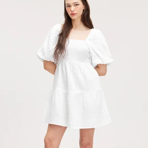 Vit kortklänning med puffärm från Monki - Superfin vit klänning från Monki med puffärmar och fyrkantig ringning. Klänningen har öppen rygg med knytband. Prislappen är kvar, då den aldrig är använd. Priset kan diskuteras