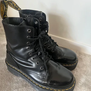 Svarta Dr. Martens Jadon boots - Säljer ett par svarta Dr. Martens Jadon boots med snörning, dragkedja på sidan och kraftig platt sula. Klassisk gul söm runt sulan och rund tå. Stl 39 
