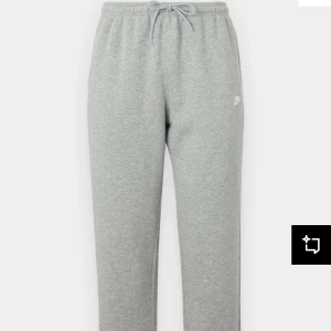 Nike tracksuit - Klassisk grå Nike tracksuit med hoodie till från Nike med luva och dragsko. Tröjan har en stor magficka framtill och en liten vit Nike-logga på bröstet. Perfekt för en avslappnad stil.