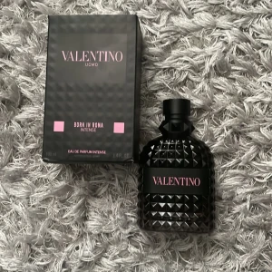 Valentino Uomo Born In Roma Intense Eau de Parfum - Exklusiv herrparfym från Valentino, Born In Roma Intense. Flaskan är svart med nitar och rosa detaljer, 100 ml. Doften är intensiv och modern, perfekt för dig som vill sticka ut med en lyxig och kraftfull signatur.