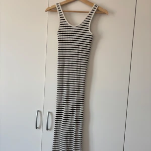 Randig ribbad långklänning - Säljer en snygg långklänning med svarta och vita ränder. Klänningen är ribbad och ärmlös med breda axelband. Perfekt för en stilren och bekväm look. Tyvärr vet jag inte storlek då jag har klippt bort etikett men skulle tippa på att den är S eller XS.
