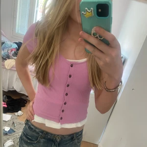 Ljuslila ribbad topp från Monki - Säljer en ljuslila ribbad topp från Monki i storlek XS. Toppen har knappar framtill. Perfekt att styla med jeans eller kjol för en trendig look.